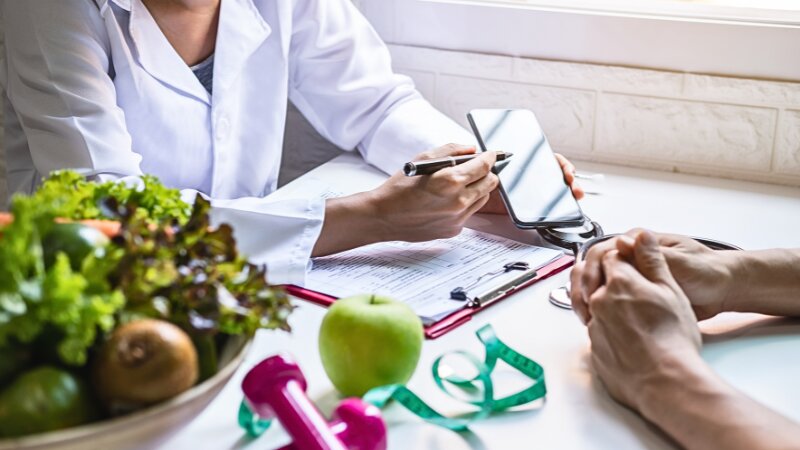 Un dentiste qui apprend à un client les bonnes habitudes alimentaires pour entretenir le sourire