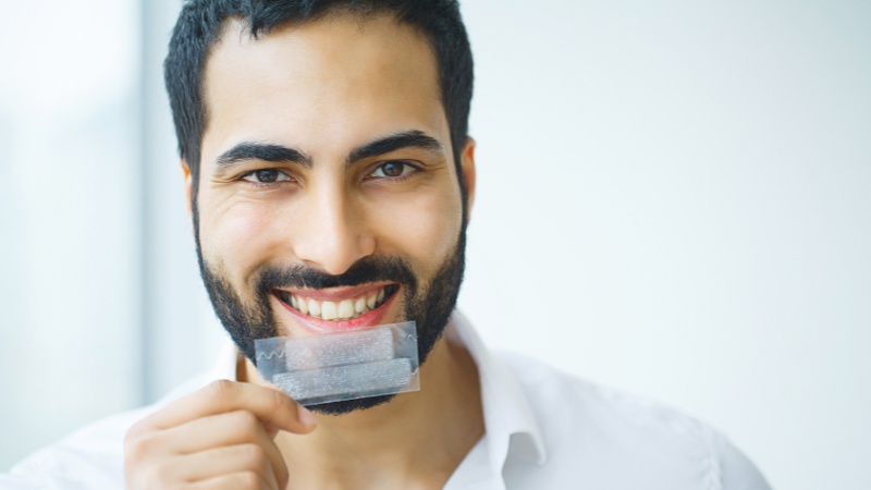 Un homme avec un strip de blanchiment dentaire