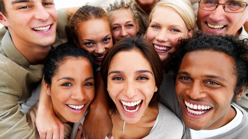 Un groupe de personnes exhibant leurs facettes dentaires en souriant