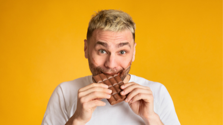 Un homme avec des implants dentaires qui croque une tablette de chocolat avec ses dents