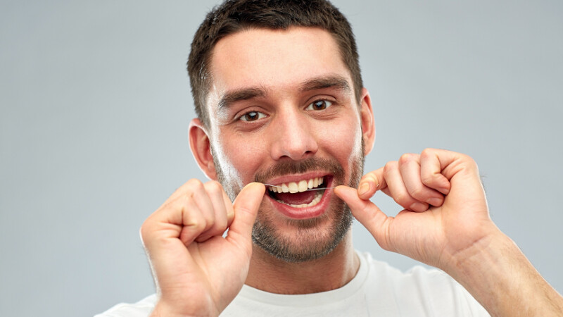 Un homme qui utilise un fil dentaire pour entretenir ses dents
