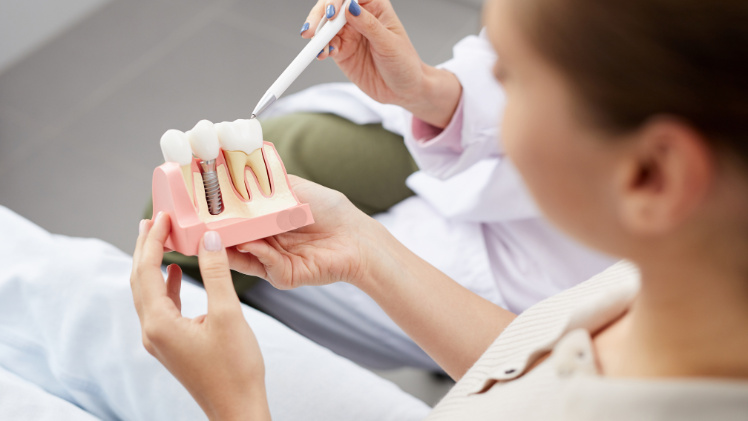 Une dentiste qui explique l'implantation dentaire à une patiente