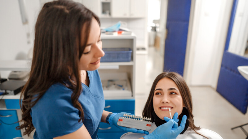 Une dentiste qui montre des facettes lumineers à une petiente