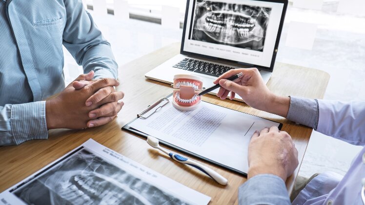 Un dentiste qui explique à un patient les alternatives à l'implant dentaire