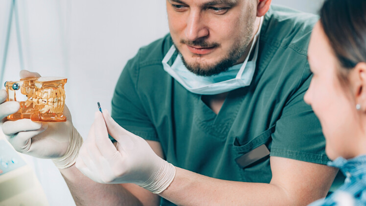 Un dentiste qui explique à une patiente le processus de pose d'un implant dentaire en titane
