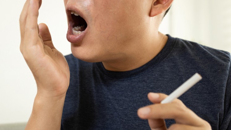 Un fumeur de cigarette qui essaye de sentir son haleine