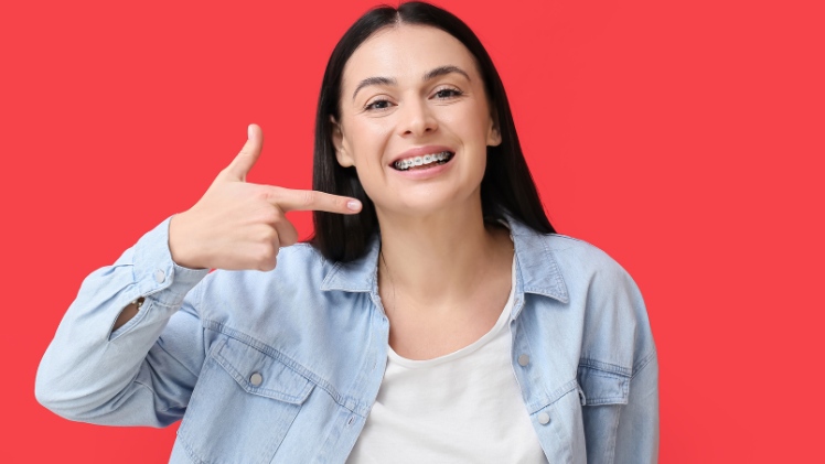 Une femme qui montre du doigt son appareil dentaire neuf