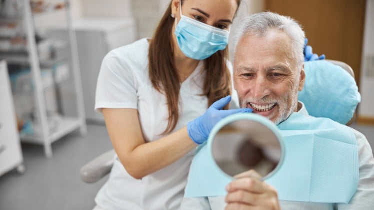 Un homme âgé qui regarde les résultats de son traitement orthodontique dentaire
