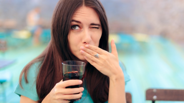Une femme avec des dents sensibles au froid et à l'acide du soda