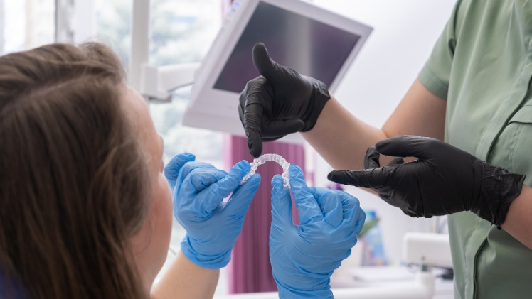 Un dentiste qui montre à sa patiente sa nouvelle gouttière dentaire