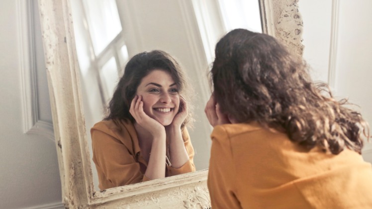 Une femme qui apprend à sourire devant le miroir