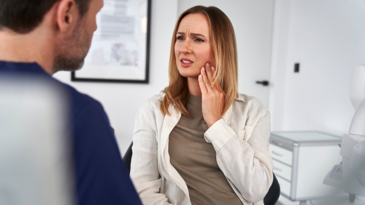 Une femme qui consulte un dentiste à cause de ses serrements dentaires