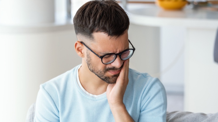 Une homme ayant des douleurs faciaux à cause de serrements dentaires