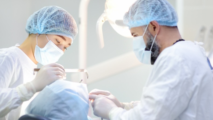 Un dentiste en train de mettre une contention dentaire fixe à un patient