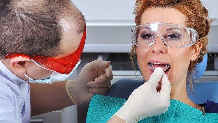 Un dentiste qui teste une gouttière amovible sur une patiente