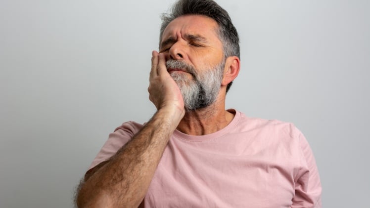 Un homme avec une inflammation des gencives à cause de ses prothèses