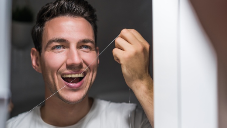 Un homme qui utilise un fil dentaire pour prévenir la gingivite