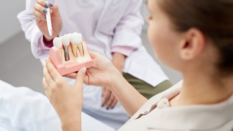 Un professionnel qui explique à une patiente le fonctionnement d'un implant dentaire