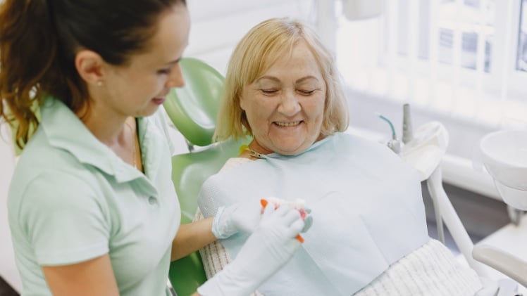 Une femme âgée qui consulte un dentiste pour réajuster sa prothèse dentaire