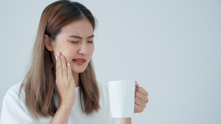 Une femme qui a une sensibilité dentaire à cause d'une gingivite
