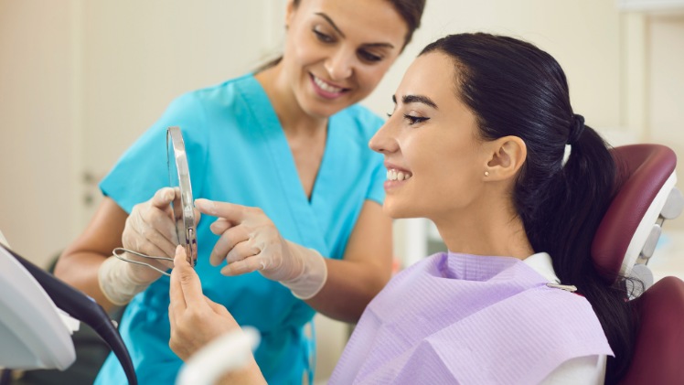 Une femme qui regarde les résultats de son opération d'implantation dentaire