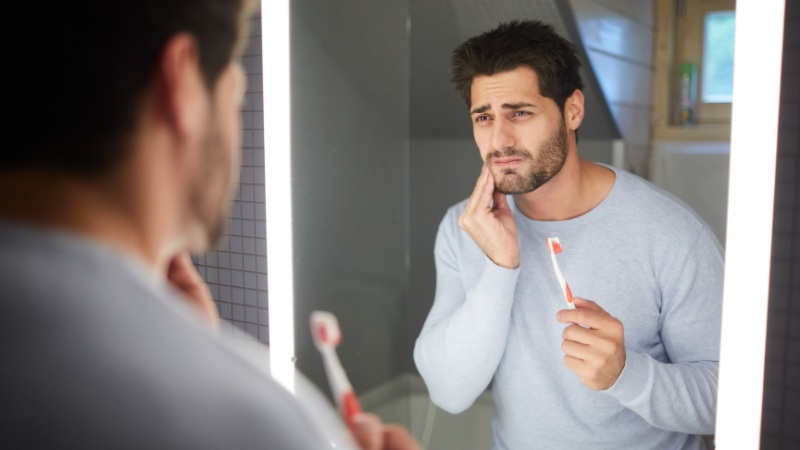 Un homme qui mange trop sucré et a les dents sensibles