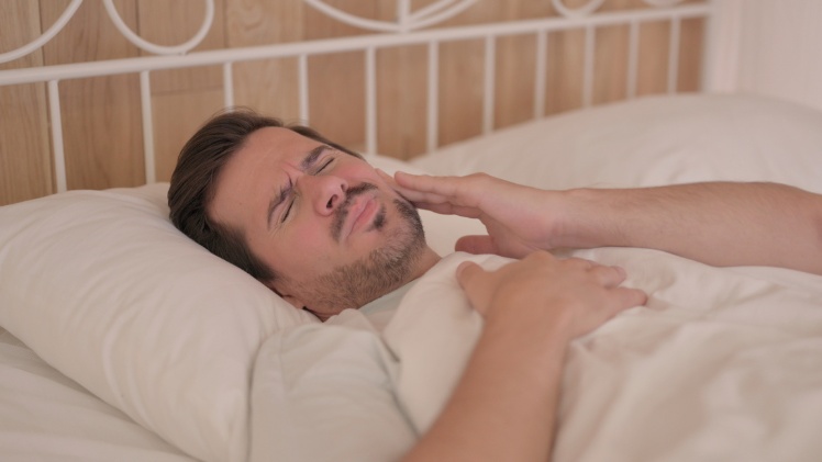 Un homme qui a des troubles du sommeil à cause de ses dents qui lui font mal