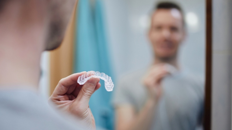 Un homme qui va mettre la gouttière dentaire pour aligner ses dents