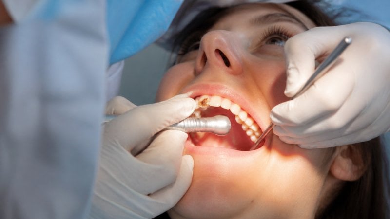 Un dentiste en train de soigner les dents d'une patiente pour lui redonner un beau sourire